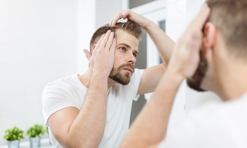 man checking hair in mirror