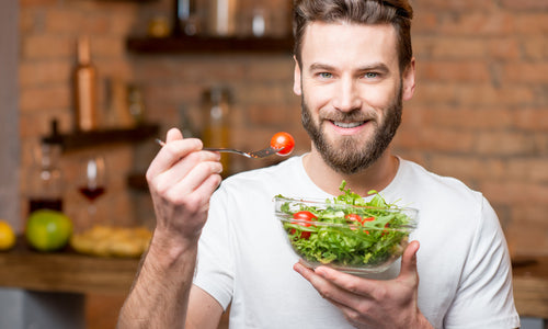 man eating salad with whole tomatoes