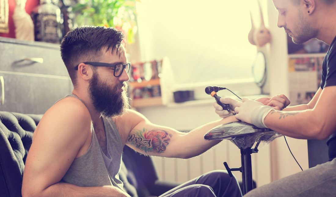 man getting tattoo on arm