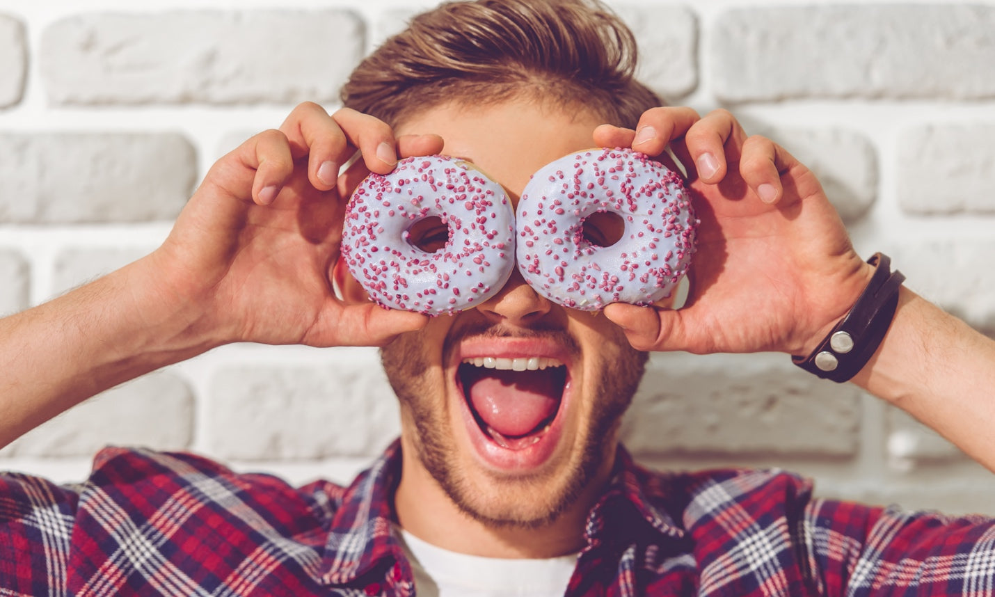 Man holding to sprinkle doughnuts over his eyes