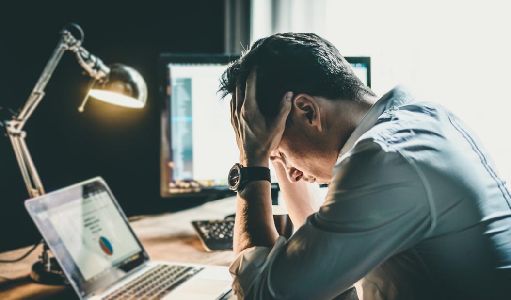 man holding head in office