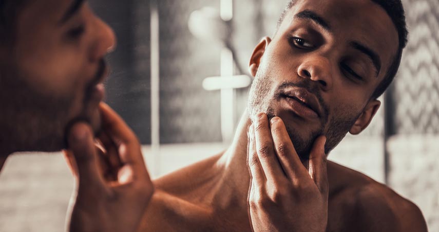 man looking at face in mirror