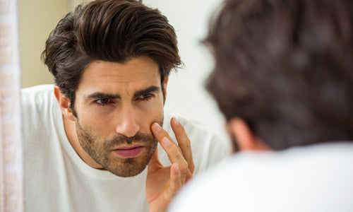 man looking at face in mirror