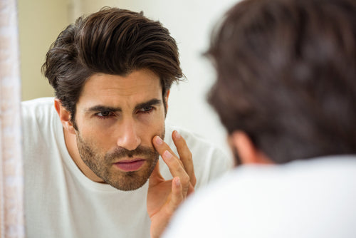 man looking at face in mirror