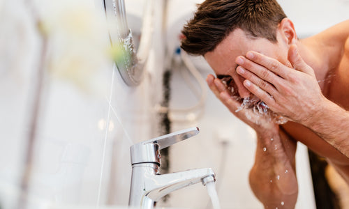 man washing face over sink