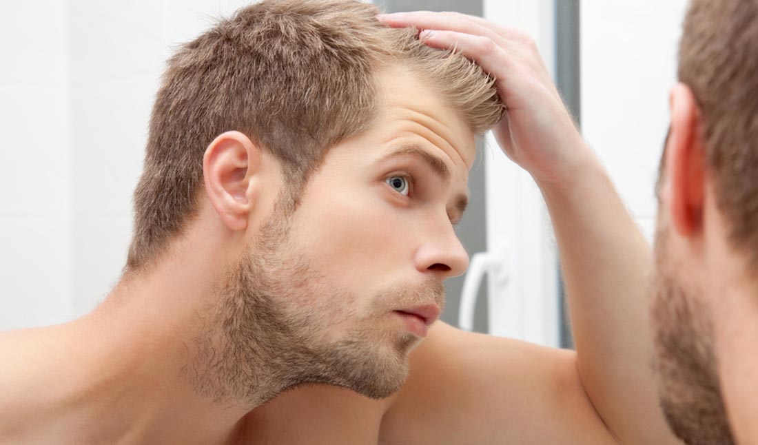 unshaven man looking in mirror