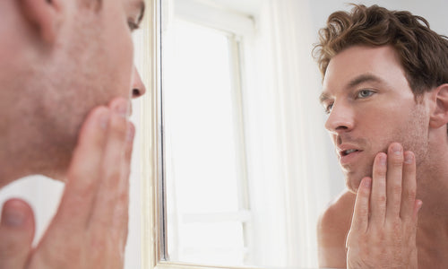 young man examining his face