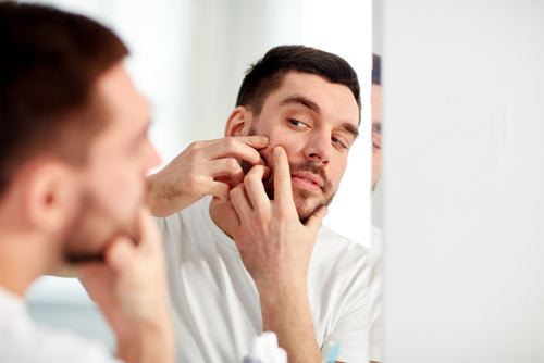 young man squeezing blemish